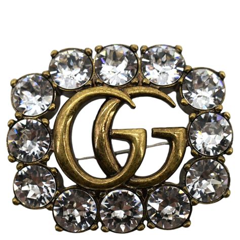 Metal Double G brooch with crystals .